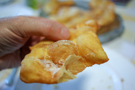 a man holding in his hand a piece of fried pastry