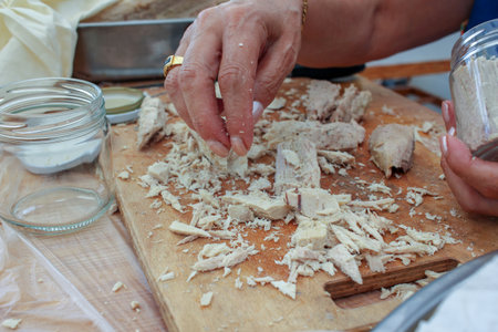 a woman is filling a glass jar with steamed bonito to preserve it in olive oil.の写真素材