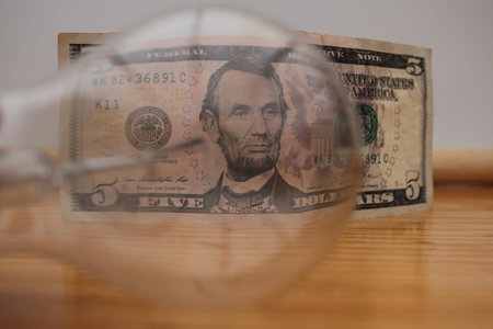Light bulbs and a five-dollar bill photographed on a neutral background.