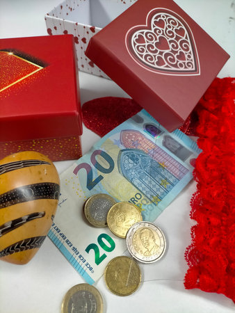 Gift box surrounded by hearts and euro banknotes representing Valentine Day spending and the cost of...