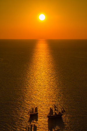 Beautiful sunset over Santorini caldera with two boats crossing, Oia, Santorini, Greeceの写真素材