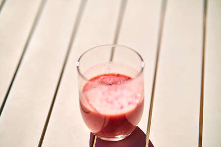 Fruit smoothie with red color on white table under sunlight