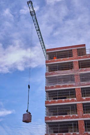 Views of a crane working on the lifting of materials during the construction of a social protection houseのeditorial素材