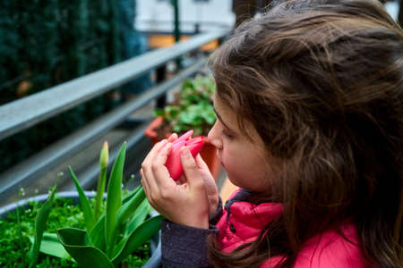 girl smelling a potted flower in early spring