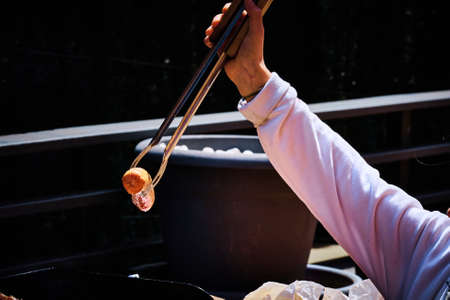 hand with a clamp placing the meat on a barbecue while cooking slowly