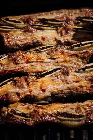 juicy beef rib and pork rib slowly being made on the grill on the fire at a gas barbecueの写真素材