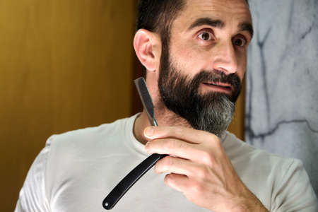 Young man in front of a mirror to wash face, shave beard or brush teeth. High quality photoの写真素材