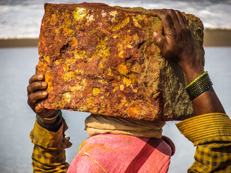 Woman carrying stone on the head in Gokarna beach Karnataka India