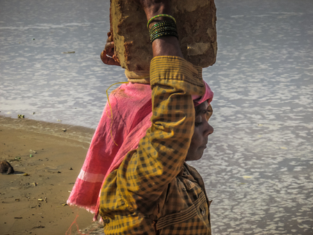 Unknowns women workers carrying stone on the head in Gokarna beach Karnataka India December 03-2017 on the morningのeditorial素材