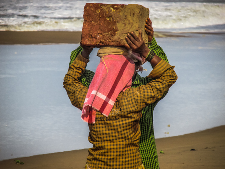 Unknowns women workers carrying stone on the head in Gokarna beach Karnataka India December 03-2017 on the morningのeditorial素材