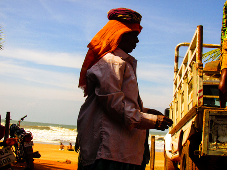 Unknown worker unloading sand from a truck at Gokarna Karnataka India December 4, 2017 morningのeditorial素材