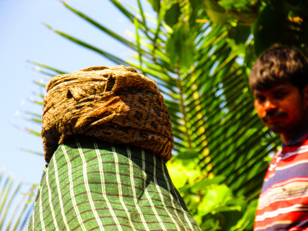Unknown worker unloading sand from a truck at Gokarna Karnataka India December 4, 2017 morningのeditorial素材