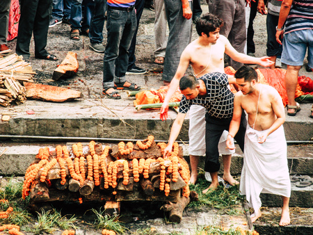 Kathmandu Nepal August 27, 2018 Hindu people attending a religious ceremony, the cremation of a dead body front the river at the Pashupatinath temple in the afternoonのeditorial素材
