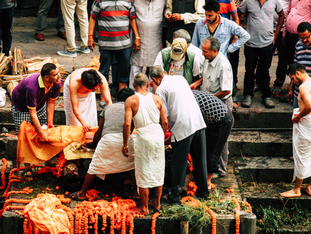Kathmandu Nepal August 27, 2018 Hindu people attending a religious ceremony, the cremation of a dead body front the river at the Pashupatinath temple in the afternoonのeditorial素材