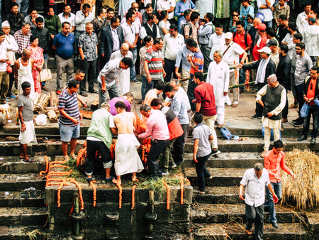 Kathmandu Nepal August 27, 2018 Hindu people attending a religious ceremony, the cremation of a dead body front the river at the Pashupatinath temple in the afternoonのeditorial素材