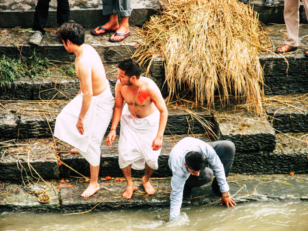 Kathmandu Nepal August 27, 2018 Hindu people attending a religious ceremony, the cremation of a dead body front the river at the Pashupatinath temple in the afternoonのeditorial素材