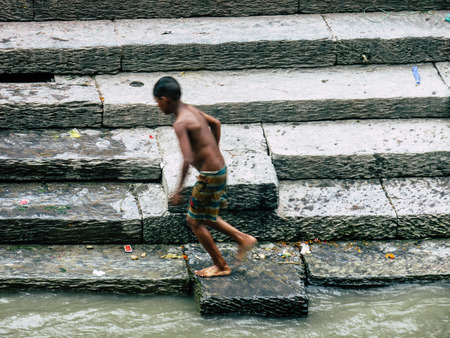 Kathmandu Nepal August 27, 2018 View of unknown Nepali taking a bath in the river at the cremation front the river at the temple of Pashupatinath in the afternoonのeditorial素材