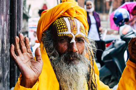 Kathmandu Nepal September 1, 2018 Portrait of a Sadhu with paint dots on the face and yellow clothes sitting at Durbar square in Kathmandu in the morningのeditorial素材