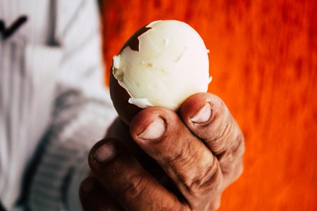 Closeup of an unknown hand holding a boiled egg in a small restaurant of Kathmandu for the breakfast in the morningの写真素材
