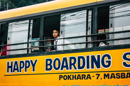 Pokhara Nepal October 4, 2018 View of a traditional Nepali yellow school bus driving in New street at pokhara in the afternoonのeditorial素材
