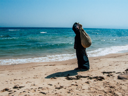 Sinai Egypt October 6, 2018 View of an Arabian women dress with burka and carrying a bag walking on the beach in the morningのeditorial素材