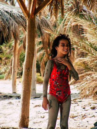 Sinai Egypt October 6, 2018 View of young happy Israeli teens with mud on the body walking on the beach in the morningのeditorial素材