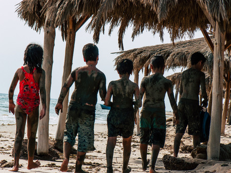 Sinai Egypt October 6, 2018 View of young happy Israeli teens with mud on the body walking on the beach in the morningのeditorial素材