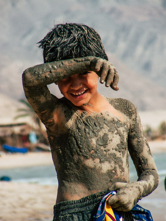 Sinai Egypt October 6, 2018 View of young happy Israeli teens with mud on the body walking on the beach in the morningのeditorial素材