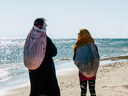 Sinai Egypt October 6, 2018 View of a young Arabian teen and a woman walking on the beach in the morningのeditorial素材