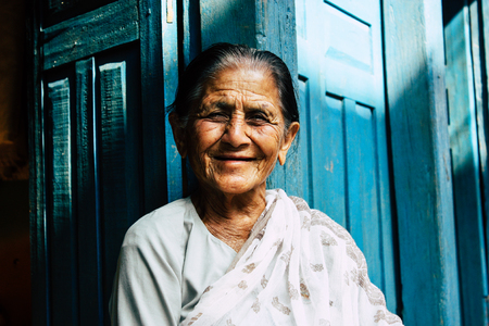Bandipur Nepal October 17, 2018 Portrait of unknown old Nepalese woman sitting front her traditional house located in the main street of Bandipur in the afternoonのeditorial素材