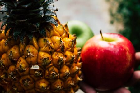 Closeup of a small pineapple and apple on nature background for healthy eating
