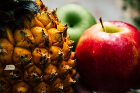Closeup of a small pineapple and apple on nature background for healthy eatingの写真素材