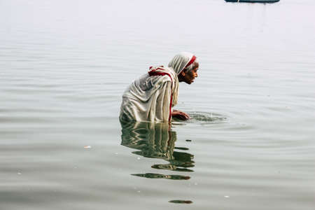 Varanasi India November 10, 2018 View of unknown old Indian woman praying in the Ganges river at Varanasi in the afternoonのeditorial素材