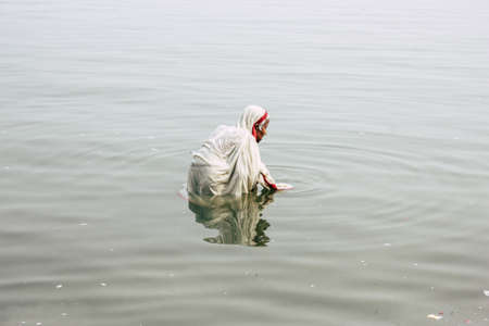 Varanasi India November 10, 2018 View of unknown old Indian woman praying in the Ganges river at...