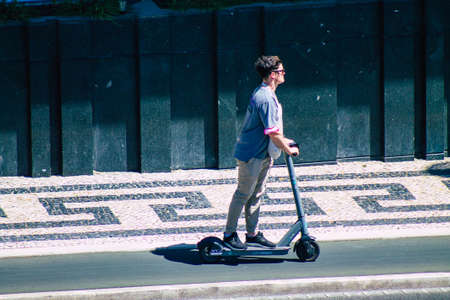 Lisbon Portugal july 25, 2020 View of unidentified people rolling with an electric scooter in the streets of Lisbon, operating with a small utility internal combustion engines and a deck in the centerの写真素材