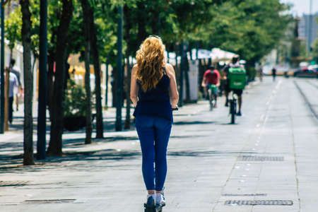Seville Spain July 02, 2021 People rolling with an electric scooter in the streets of Seville, operating with a small utility internal combustion engines and a deck in the centerの写真素材