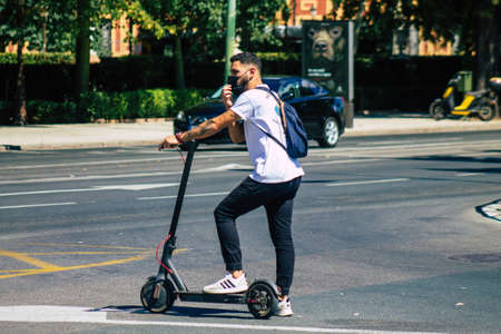 Seville Spain July 06, 2021 People rolling with an electric scooter in the streets of Seville, operating with a small utility internal combustion engines and a deck in the centerの写真素材