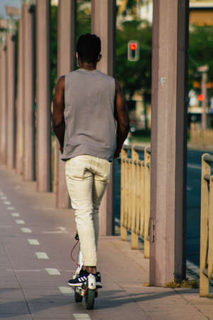 Seville Spain July 23, 2021 People rolling with an electric scooter in the streets of Seville, operating with a small utility internal combustion engines and a deck in the centerの写真素材