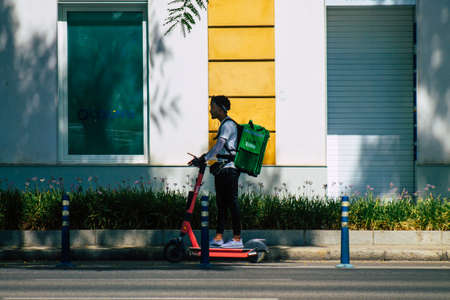Seville Spain August 21, 2021 People rolling with an electric scooter in the streets of Seville, operating with a small utility internal combustion engines and a deck in the centerの写真素材