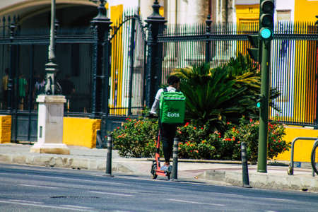 Seville Spain August 21, 2021 People rolling with an electric scooter in the streets of Seville, operating with a small utility internal combustion engines and a deck in the centerの写真素材