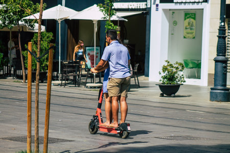 Seville Spain August 21, 2021 People rolling with an electric scooter in the streets of Seville, operating with a small utility internal combustion engines and a deck in the centerの写真素材