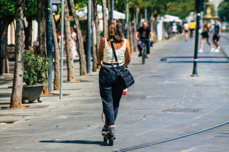 Seville Spain August 21, 2021 People rolling with an electric scooter in the streets of Seville, operating with a small utility internal combustion engines and a deck in the centerの写真素材