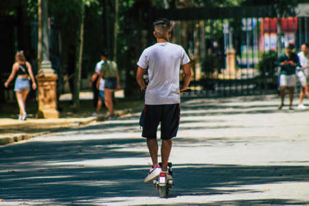 Seville Spain August 28, 2021 People rolling with an electric scooter in the streets of Seville, operating with a small utility internal combustion engines and a deck in the centerの写真素材