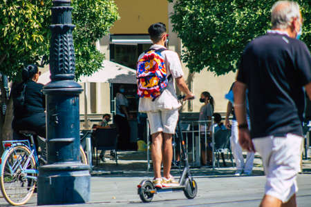 Seville Spain August 28, 2021 People rolling with an electric scooter in the streets of Seville, operating with a small utility internal combustion engines and a deck in the centerの写真素材