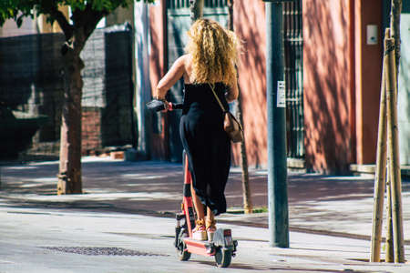 Seville Spain September 04, 2021 People rolling with an electric scooter in the streets of Seville, operating with a small utility internal combustion engines and a deck in the centerの写真素材