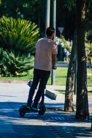 Seville Spain September 04, 2021 People rolling with an electric scooter in the streets of Seville, operating with a small utility internal combustion engines and a deck in the centerの写真素材
