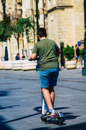 Seville Spain September 18, 2021 People rolling with an electric scooter in the streets of Seville, operating with a small utility internal combustion engines and a deck in the centerのeditorial素材