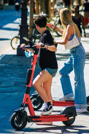 Seville Spain September 18, 2021 People rolling with an electric scooter in the streets of Seville, operating with a small utility internal combustion engines and a deck in the centerのeditorial素材