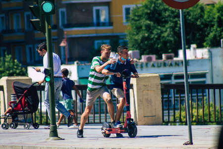 Seville Spain September 04, 2021 People rolling with an electric scooter in the streets of Seville, operating with a small utility internal combustion engines and a deck in the centerのeditorial素材