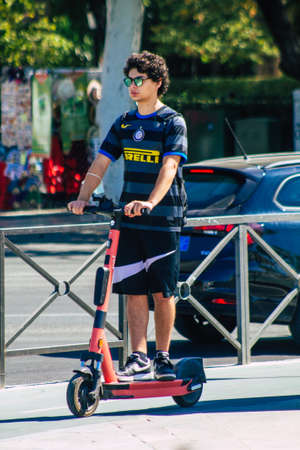 Seville Spain September 04, 2021 People rolling with an electric scooter in the streets of Seville, operating with a small utility internal combustion engines and a deck in the centerのeditorial素材